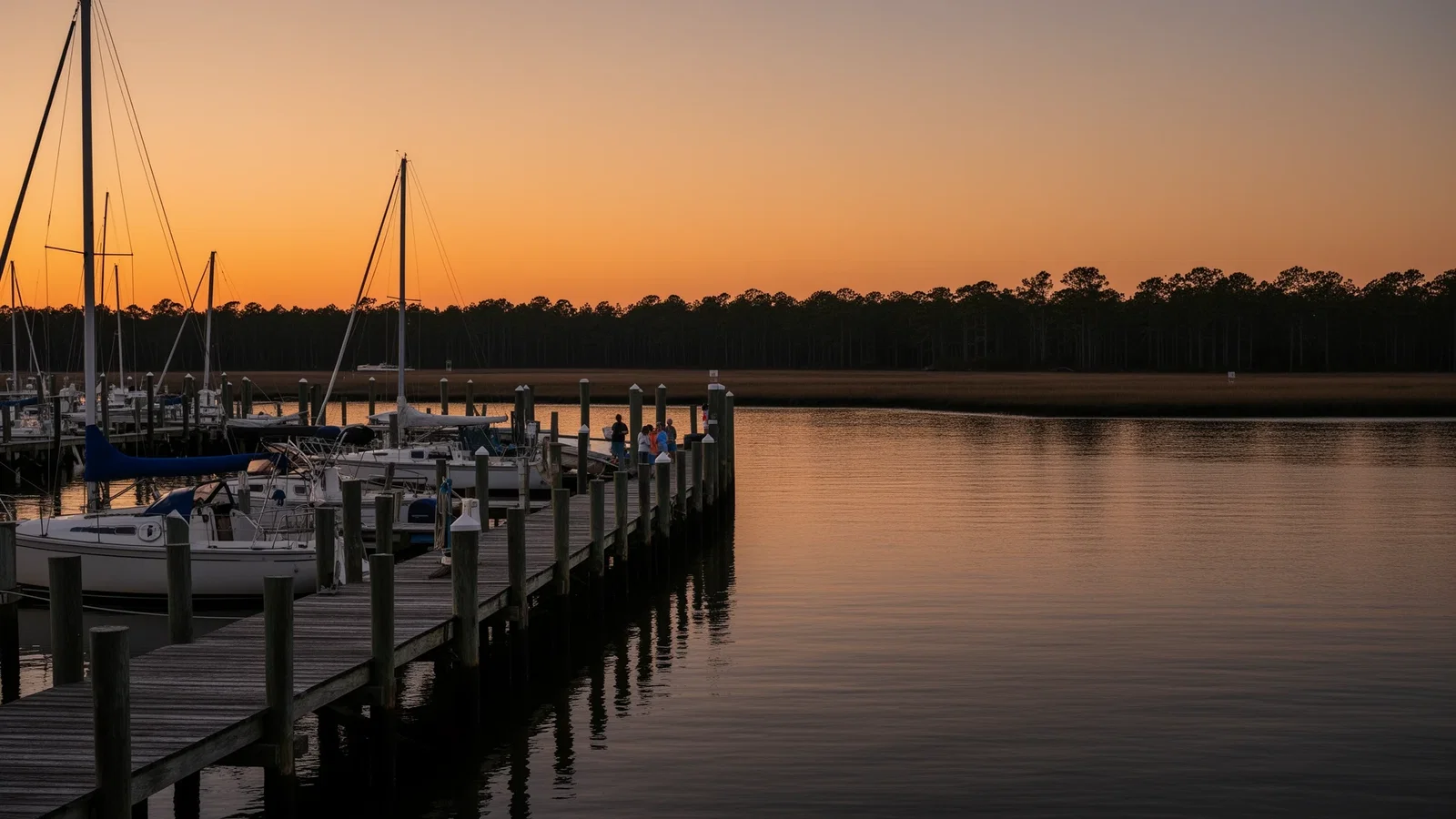 A marina on the Pasquotank River in Elizabeth City at dusk with sailboat masts and harbor lights